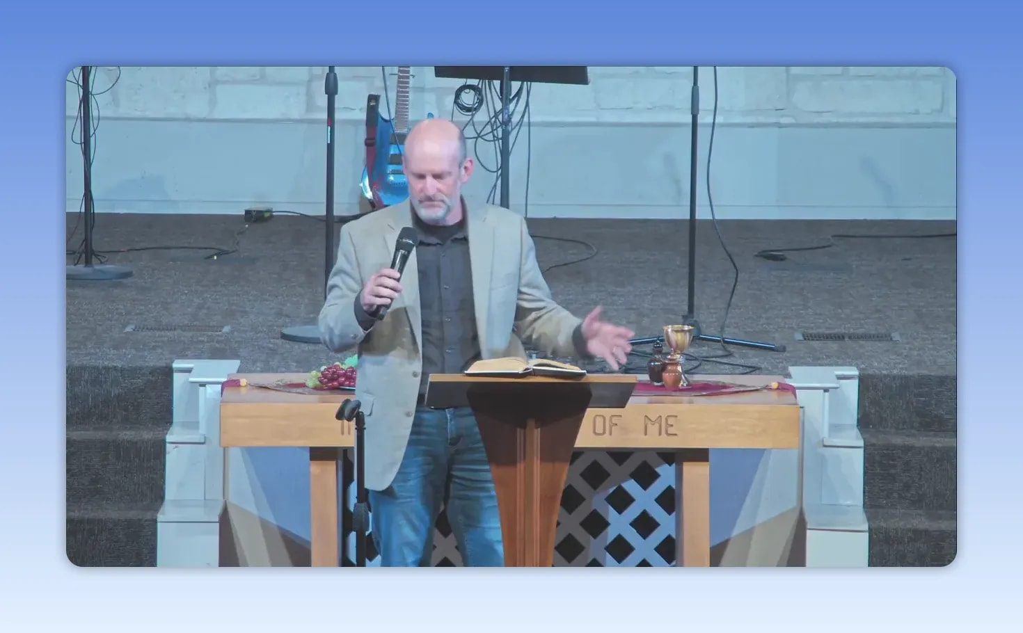 Pastor pointing while speaking at the pulpit with an open Bible during a sermon on honoring mothers