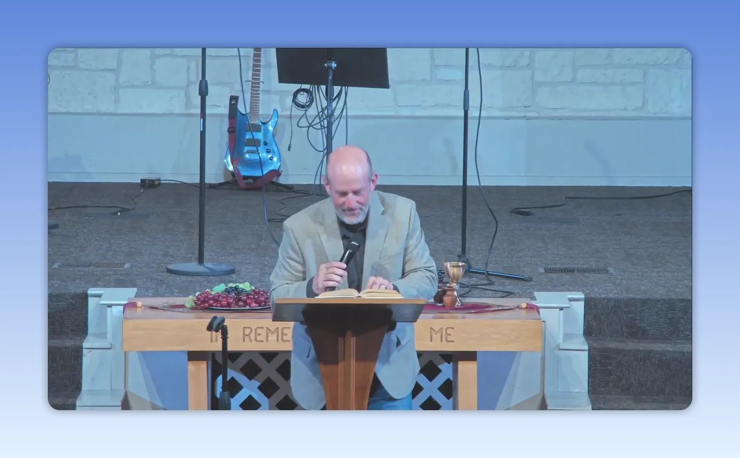 Pastor reading from an open Bible at the lectern during a sermon on why motherhood matters
