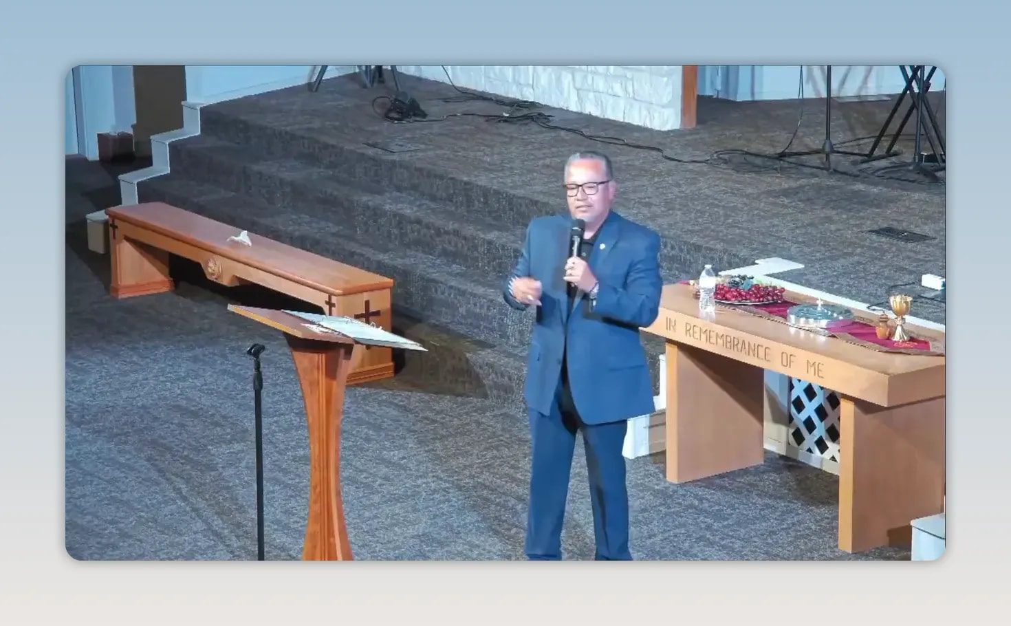 Pastor speaking beside a wooden lectern and communion table
